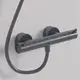 Brausethermostat von Ideal Standard in Magnetic Grey mit zwei runden Bedienelementen und flexibler Verbindung zu einer Brause. Wandmontage sichtbar.